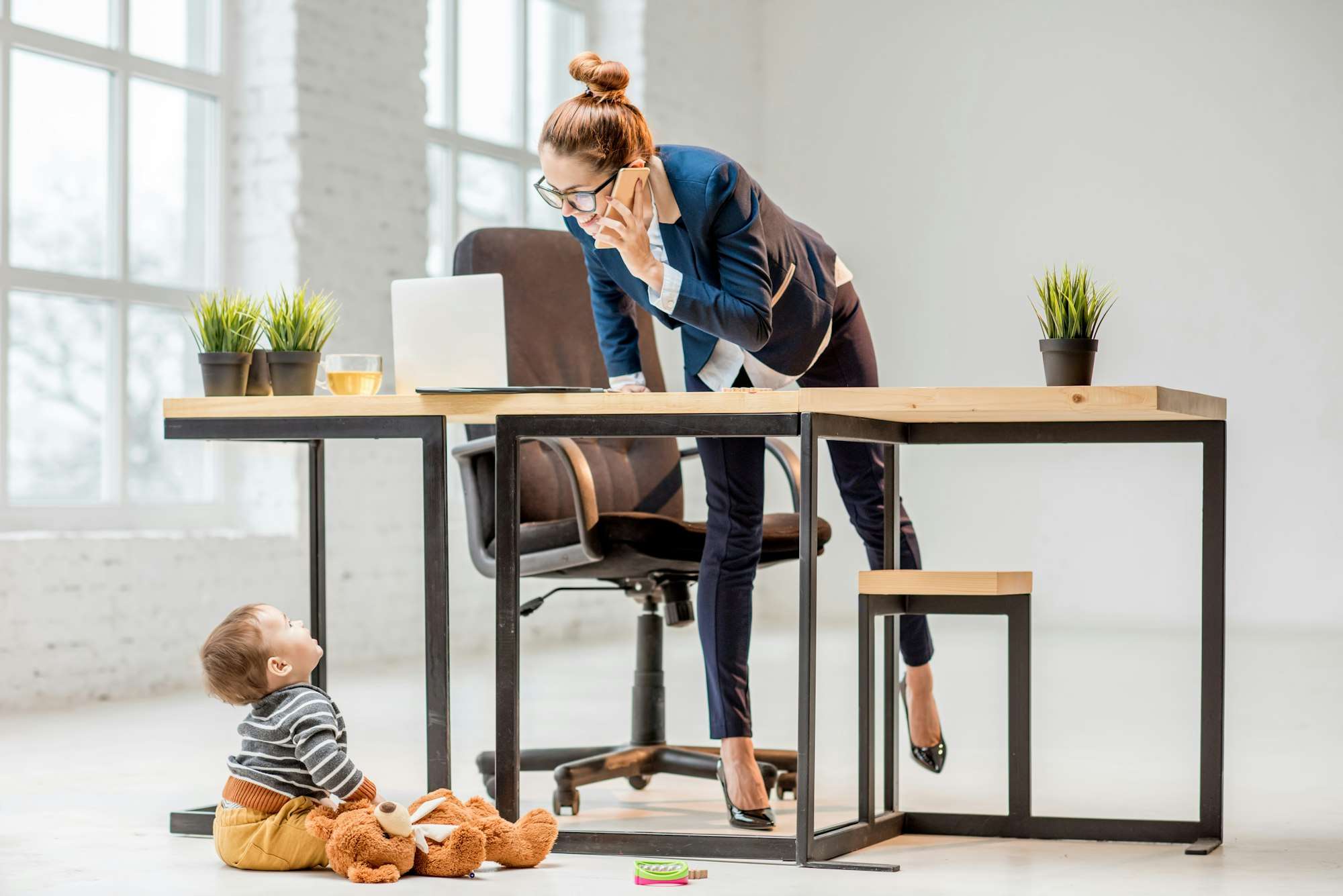 Multitasking businesswoman with her son at the office