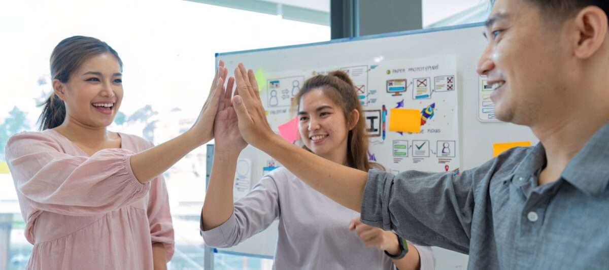 8 Ways Freshchat Outperforms Tidio for Website Chat and Support Your Team Needs to Know 1 Group of designer cheerful giving high five on the success of website design and application on