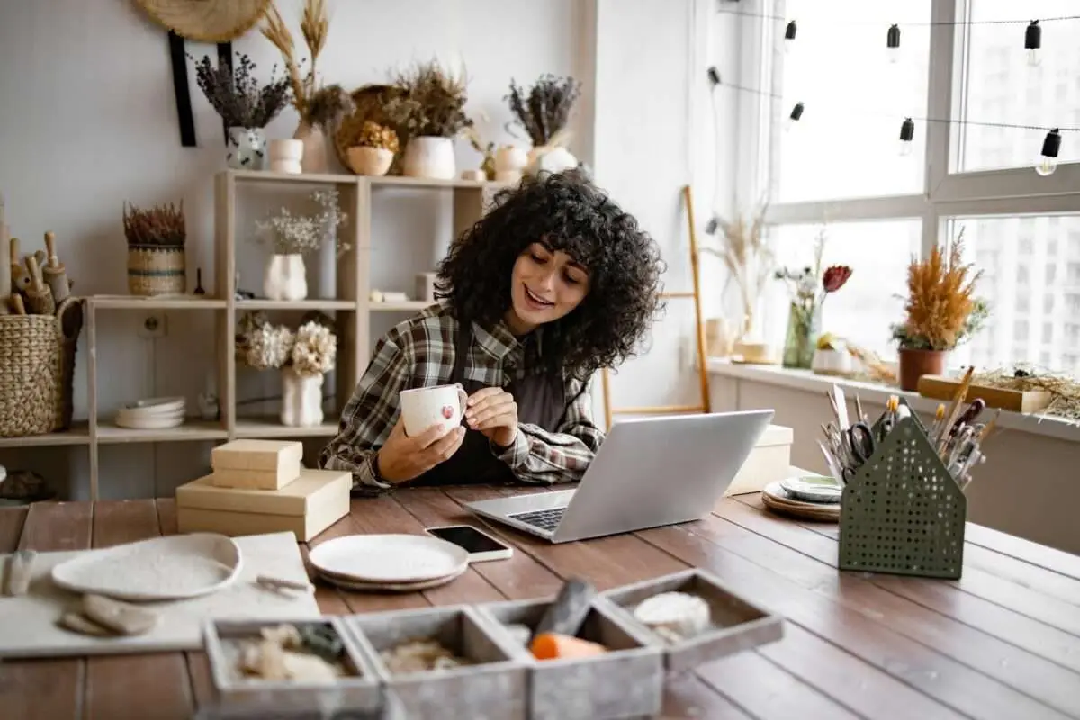Young ceramic shop owner using laptop while working in store using content promotion strategies